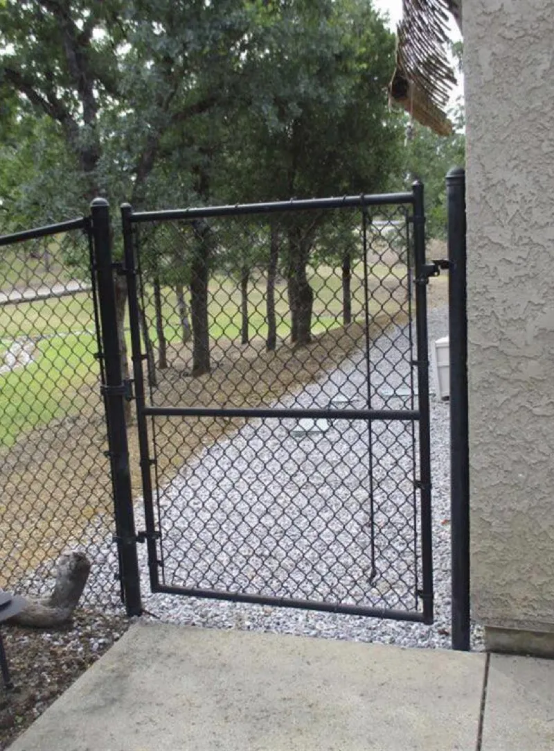 Metal chain-link gate properly connected to stucco wall as noncombustible fencing